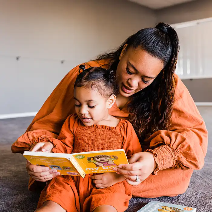 An adult and a child reading a book together. 