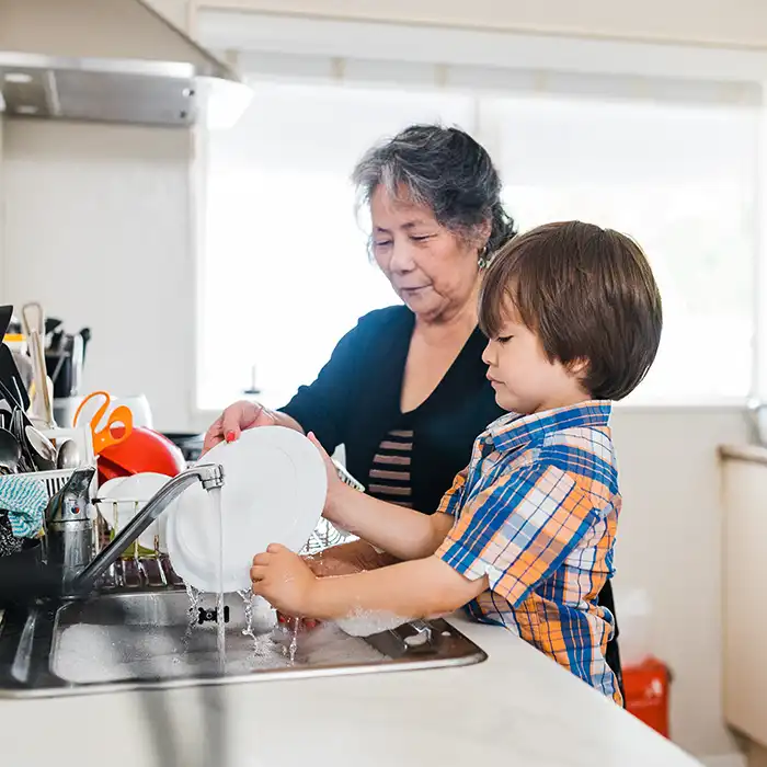 A child and an adult washing dishes. 