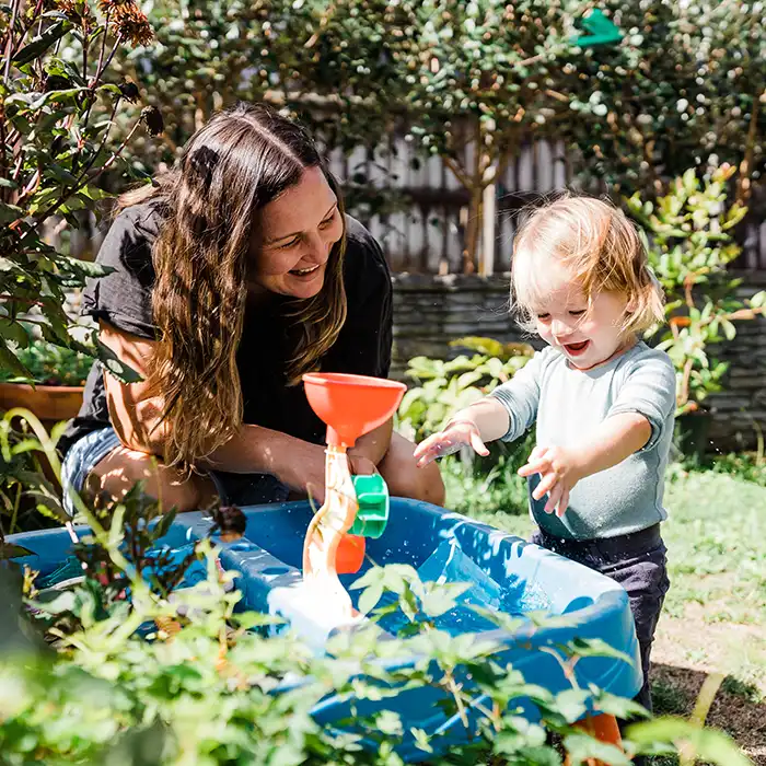 An adult and a child playing with water in the garden. 