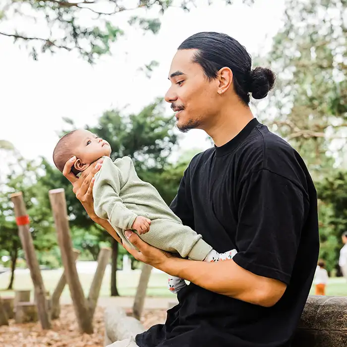 An adult outside holding a baby. 