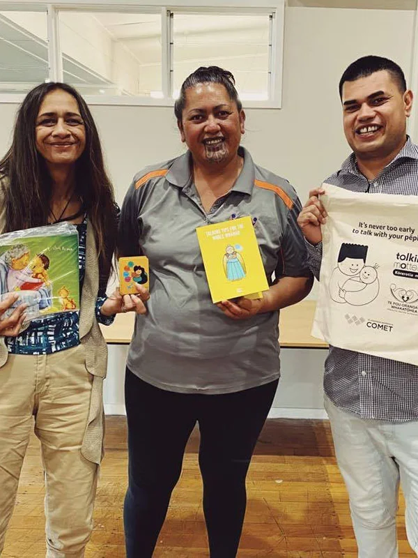 Two whānau workers hold Tākai and Talking Matters resources with Anthony Quinn-Cowley