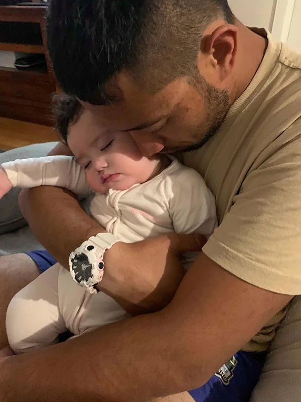 A father cuddles his sleeping pepi.