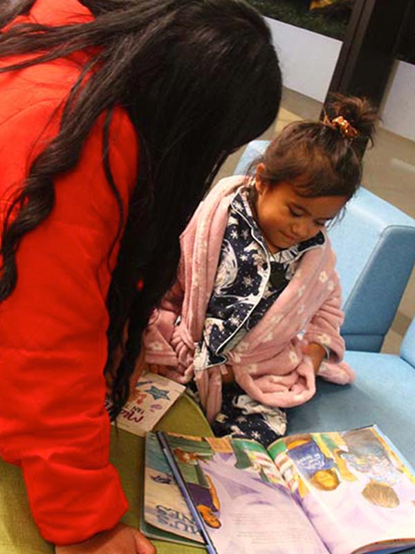 Mum and daughter reading book at the library
